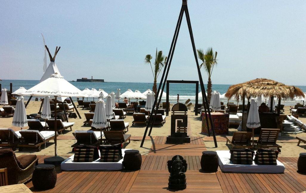Plage privée avec transats, parasols blancs et tipis face au fort de Brescou